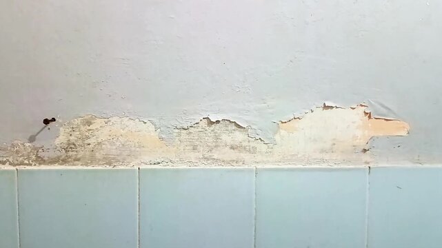 Close-up of peeling paint texture on light blue wall