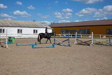 Fototapeta premium Little girl learning horseback riding with trainer on farm arena