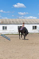Child horse riding lesson with instructor in sunny outdoor equestrian arena