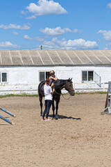 Child horse riding lesson with instructor in sunny outdoor equestrian arena