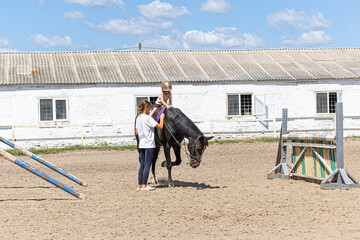 Child horse riding lesson with instructor in sunny outdoor equestrian arena