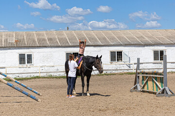 Child horse riding lesson with instructor in sunny outdoor equestrian arena