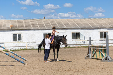 Child horse riding lesson with instructor in sunny outdoor equestrian arena