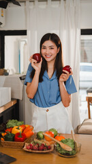 Young woman holding two red apples promoting healthy eating in kitchen