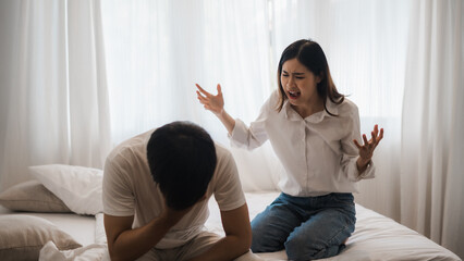 Young asian woman arguing with her boyfriend sitting on bed at home