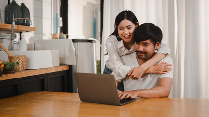 Asian couple using laptop together in kitchen