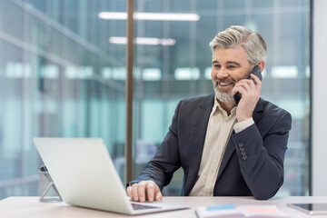 Confident businessman on a call while working on his laptop in office