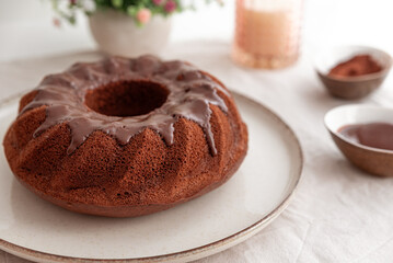 Chocolate cake with chocolate icing on white wooden table.