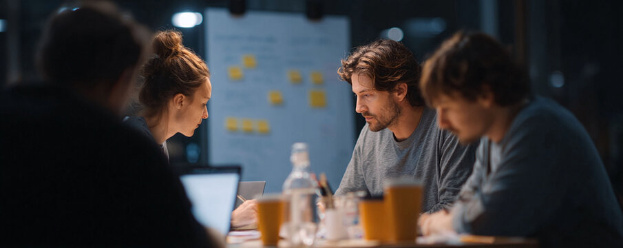 Focused team collaboratively brainstorming at night. Agile workflow concept, idea generation, and strategic planning. Represents teamwork and innovation.