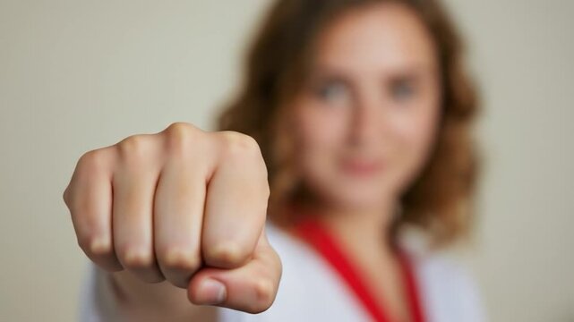 Woman show fist demonstrating confidence and strength in a brightly lit studio setting