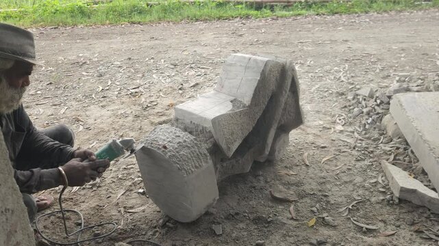 Stone Carving - Stone Art in India. Indian stone mason Creating abstract sculpture Of granite Stone. Cutting rock with grinder, chisel and hammer with traditional technique.