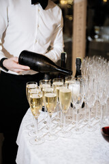 Waiter pouring champagne into flutes at elegant evening reception event