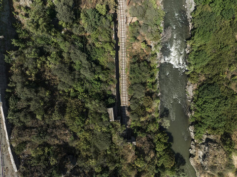 Aerial view of a railway bridge piercing through a dense forest, connecting to the opposite bank of a river, Lori, Lori Province, Armenia.