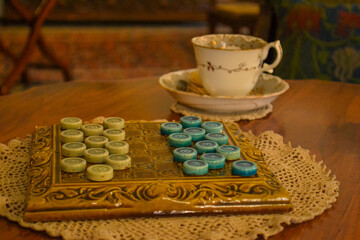 Vintage board game with porcelain teacup on wooden table
