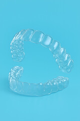 3D render of transparent dental aligners isolated on blue background, orthodontic appliance for modern teeth correction.
