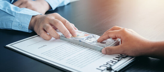 Close up of businessman offering bribe banknote to man employee to signing the contract to joint engage