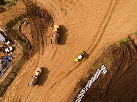 Aerial view of dump trucks transporting dirt around construction site for building bypass