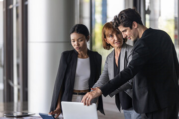 Conversation or group discussion among business team members from different generations, cultures, and diverse ethnicities outside of the main office. Group of people use computer to get information
