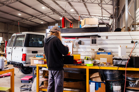 Young male mechanic working on wiring for vehicle beacon light for light bar on workbench