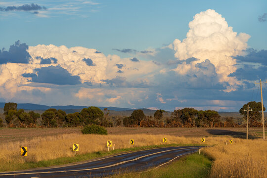 Traffic signs along the side of a country road under dramatic storm clouds