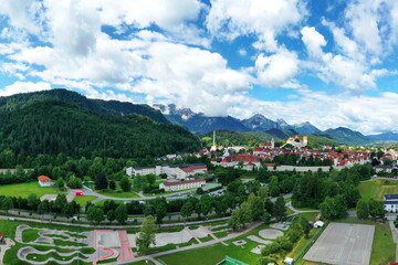 Sportanlage mit Fußballfeld, Laufbahn und Baseballplatz vor idyllischer Bergkulisse bei Füssen – eingebettet in grüne Natur mit Hügeln und Wolkenstimmung.
