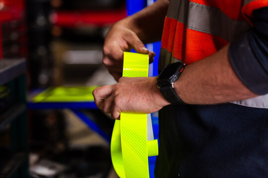 Workman cutting reflective tape for installation on mining fleet vehicle for safety in workshop