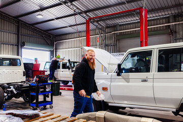 Happy smiling australian mechanic in industrial workshop shed