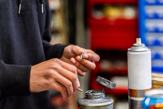 Mechanics hands holding small mechanical part beside workbench