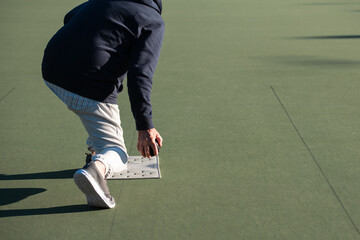 Senior Woman Bowling on Green Court with Ball and Mat
