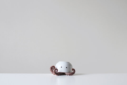 Conceptual octopus with Octopus tentacles under an upside down bowl with two eyes