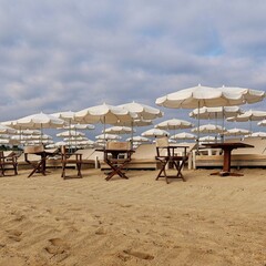 Wooden chairs and white umbrellas on an empty beach at the end of summer season in Ramatuelle, Saint-Tropez, Côte d’Azur, France, 26 August 2025. Seasonal tourism concept.
