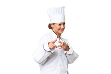 Middle-aged chef woman over isolated background pointing to the front and smiling