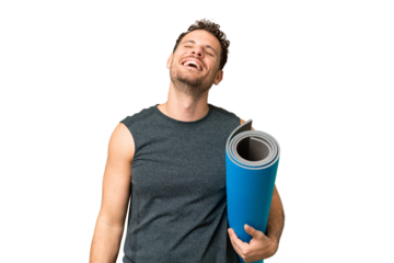 Young sport man going to yoga classes while holding a mat over isolated chroma key background laughing