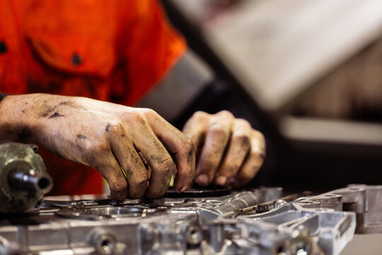 Aussie mechanics hands covered in grease working on car engine repairs in workshop