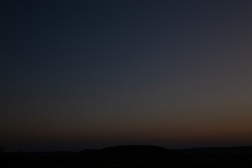 Crescent moon and twilight sky over the silhouette of the landscape.