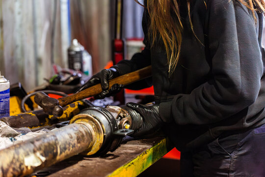 Female Australian mechanic working on vehicle driveshaft joint repairs in workshop