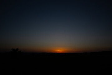 The sun descends, creating a breathtaking sunset over a serene landscape.