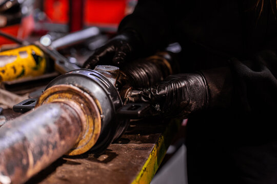 Australian mechanic working on vehicle driveshaft joint repairs in workshop