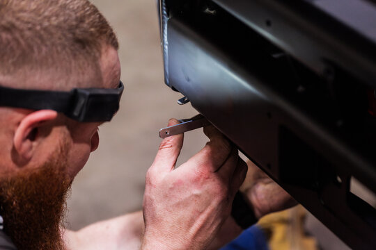 Australian man installing bull bar onto vehicle in mechanic workshop
