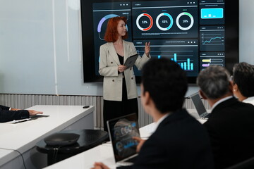 Female business colleagues and female marketing staff talking, consulting, looking at graphs, analyzing, planning work together, monitoring stock trading in the market, company desk.