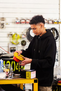 Young male mechanic holding a mining vehicle light inside workshop testing parts before installation