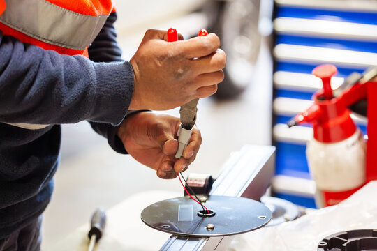 Male technician working on the wiring on circular metal plate for light bar