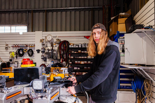 young Aussie man working in mechanics workshop building part of light bar of vehicle