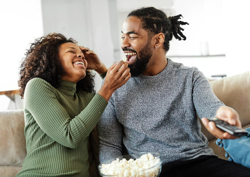 Portrait of a happy young couple watching tv together at home. Shot of a couple resting on the couch watching television