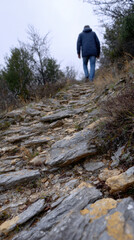 Fototapeta premium Hiker on rocky trail in nature, wearing jacket and jeans