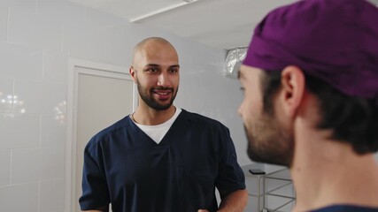 Two medical professionals converse in a hospital setting, possibly discussing a patient's condition or a medical procedure. Two medical professionals converse in a hospital setting