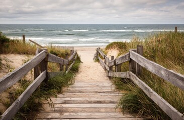 Wooden steps leading down to a sandy beach, ocean waves visible in the distance