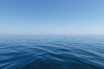 Obraz premium Vast expanse of deep blue ocean meets a clear, pale blue sky. Distant, hazy landforms are barely visible