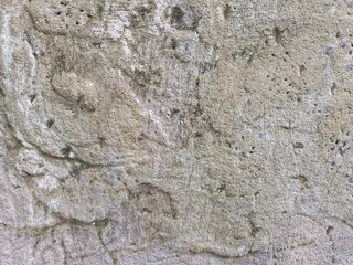 textured, rough concrete or stucco surface. The surface is uneven and includes small holes and a few darker patches