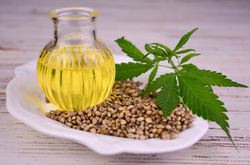 Hemp seeds and hemp seed oil on white wooden background.
